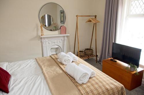 a bedroom with towels on a bed with a mirror at Coney Cottage in Porthcawl