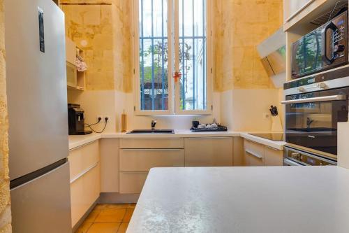une cuisine avec des placards blancs et un comptoir blanc dans l'établissement Villa Place St Pierre - Bordeaux Centre - 4 pers, à Bordeaux