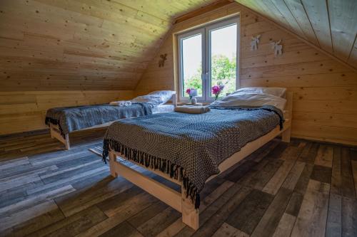 2 łóżka w drewnianym pokoju z oknem w obiekcie Groszkówka w mieście Narewka