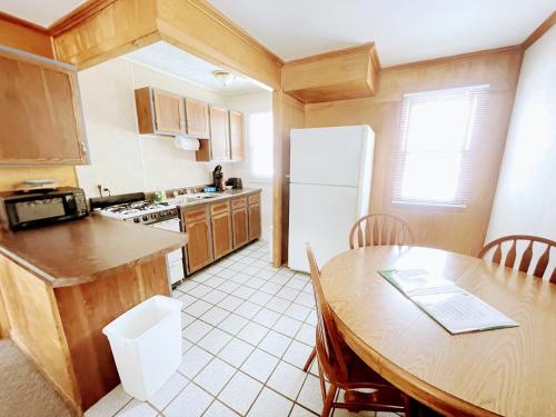 a kitchen with a table and a white refrigerator at Hillcrest Inn & Motel in Rapid River