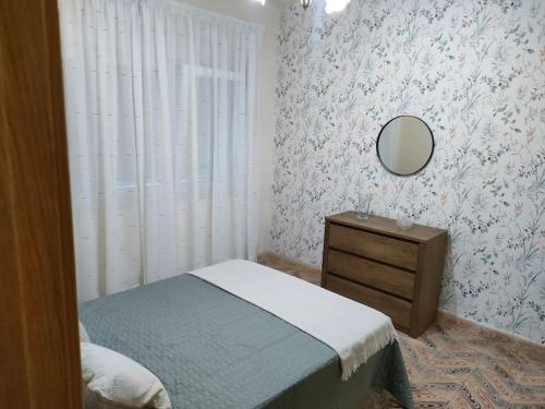 ein Schlafzimmer mit einem Bett, einem Spiegel und einer Kommode in der Unterkunft Piso centrico en Ribadeo in Ribadeo