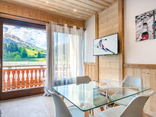 une salle à manger avec une table et des chaises en verre ainsi qu'une fenêtre dans l'établissement Grand Studio cabine, balcon, parking, centre La Clusaz - FR-1-437-85, à La Clusaz