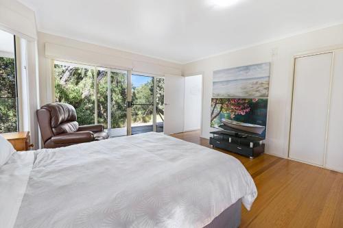 a bedroom with a bed and a television and a chair at Acacia Lakehouse in Goon Nure