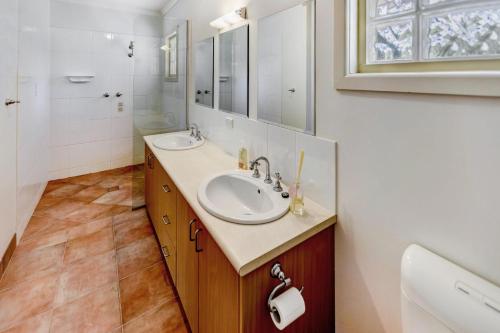 a bathroom with two sinks and a mirror at Acacia Lakehouse in Goon Nure