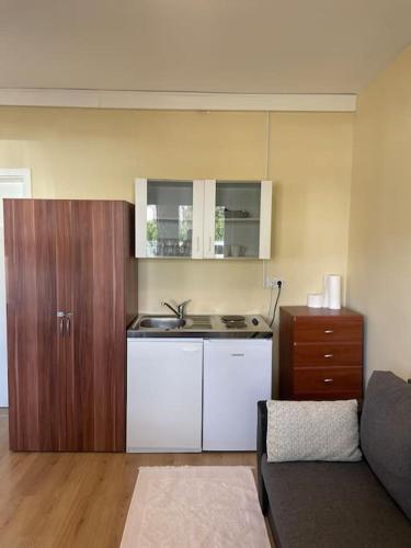 eine Küche mit weißen Schränken, einer Spüle und einer Couch in der Unterkunft Einzimmerwohnung + Dusche und WC in Berlin