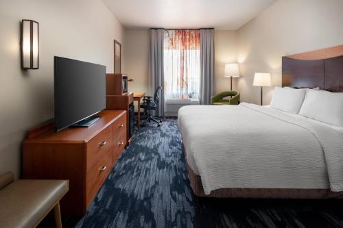a hotel room with a bed and a flat screen tv at Fairfield Inn & Suites by Marriott Visalia Tulare in Tulare