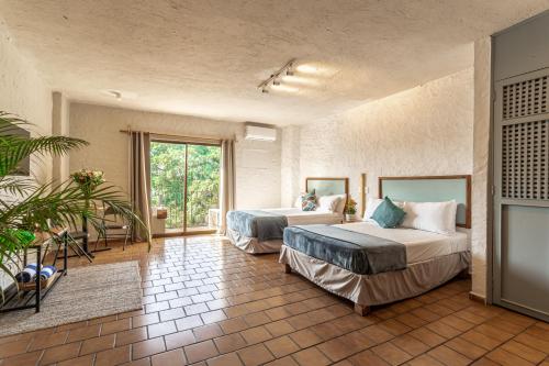 Cette chambre comprend deux lits et une grande fenêtre. dans l'établissement Soy Local Puerto Vallarta, à Puerto Vallarta
