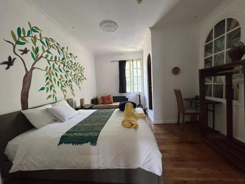 a bedroom with a bed with a tree mural on the wall at Hotel Boutique Spa Villa de Sant in Quito
