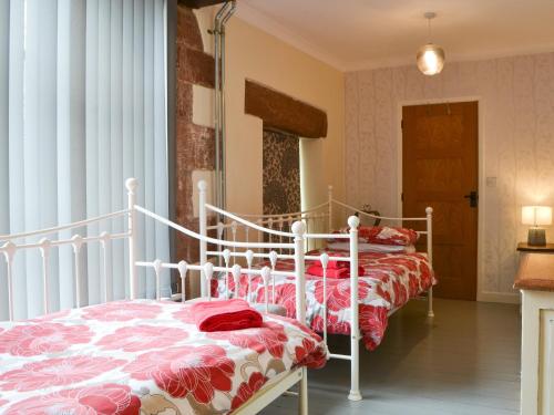 1 dormitorio con 2 camas y mantas rojas y blancas en The Coach House, en Blencogo