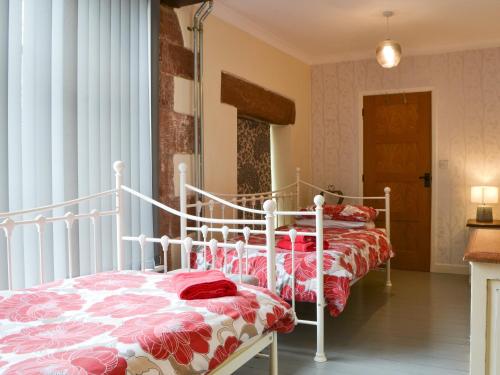 a bedroom with two beds with red and white blankets at The Coach House in Blencogo