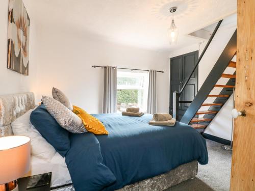 a bedroom with a blue bed and a staircase at 13 The Square in Oakamoor