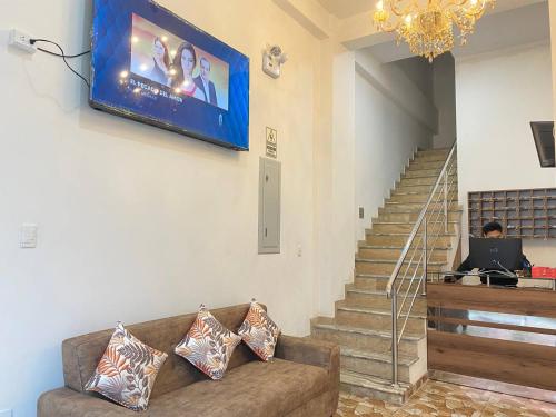 a living room with a couch and a television on the wall at Hotel Los Pajonales in Huaraz