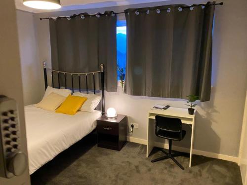 a bedroom with a bed and a desk and a window at Culbin Lodge in Glasgow