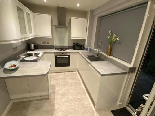 a kitchen with white cabinets and a large window at Culbin Drive, Glasgow in Glasgow