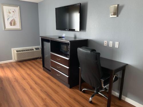 a room with a desk with a television and a chair at Rodeway Inn & Suites Port Arthur - Groves in Port Arthur