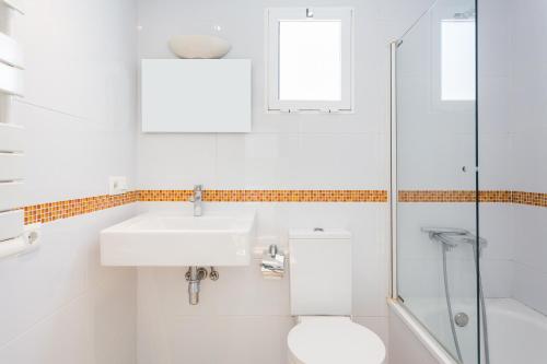 a white bathroom with a sink and a toilet at Villa Dimarts- a 100m de playa in Gandía