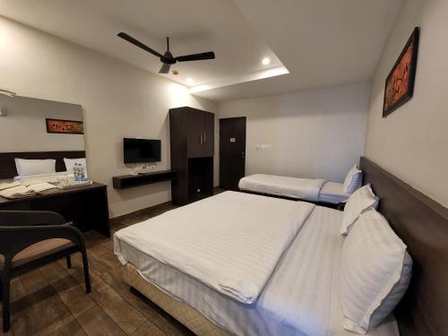 a hotel room with two beds and a desk and a tv at HOTEL PARK KRISHNA in Tirupati