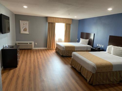 a hotel room with two beds and a window at Rodeway Inn & Suites Port Arthur - Groves in Port Arthur