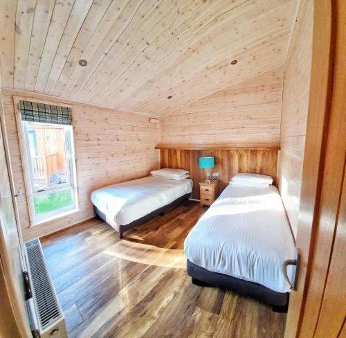 two beds in a room with wooden walls at MAC Skyline Lodges in Balloch