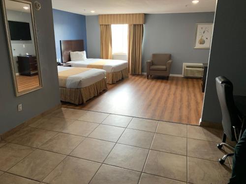 een hotelkamer met 2 bedden, een stoel en een spiegel bij Rodeway Inn & Suites Port Arthur - Groves in Port Arthur