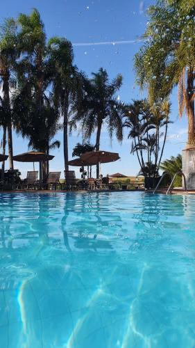 a large blue swimming pool with chairs and umbrellas at Panorama Park Hotel in Igarassú
