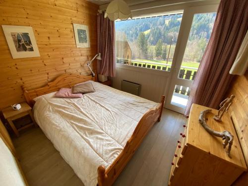 une chambre avec un lit et une grande fenêtre dans l'établissement Charmant 2 pièces avec balcon - Multi Pass 3€/jour/personne - FR-1-692-36, à La Chapelle-dʼAbondance