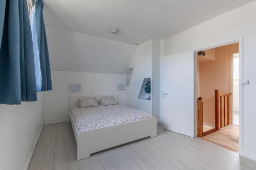 ein Schlafzimmer mit einem Bett in einem weißen Zimmer in der Unterkunft La maison des dunes - Proche plage pour 6 in Courseulles-sur-Mer