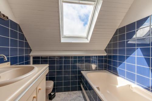 ein Bad mit einer Badewanne, einem Waschbecken und einem Fenster in der Unterkunft La maison des dunes - Proche plage pour 6 in Courseulles-sur-Mer