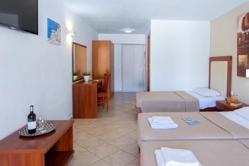 a hotel room with two beds and a table with a bottle of wine at Xidas Garden in Balíon