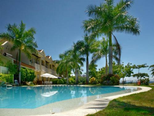 a swimming pool with palm trees next to a building at Mactan Island Condo La Mirada Residence , Beach resort , Large 1 bedroom , pools , Ocean views, fast WiFi , Netflix in Mactan