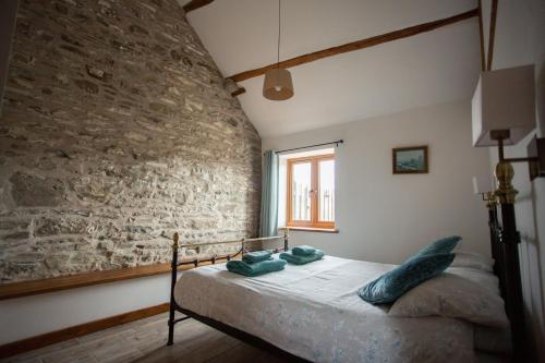 a bed in a room with a stone wall at 1 Beacon View Barn in Felindre