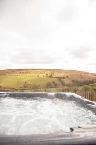 a hot tub with water and a field in the background at 1 Beacon View Barn in Felindre