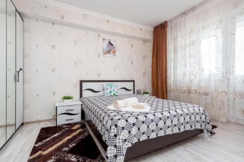 um quarto com uma cama com uma colcha preta e branca em Светлая квартира рядом с парком Горького em Almaty