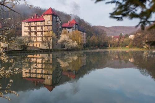 a reflection of a building in a lake at Ruta Resort Polyana in Polyana