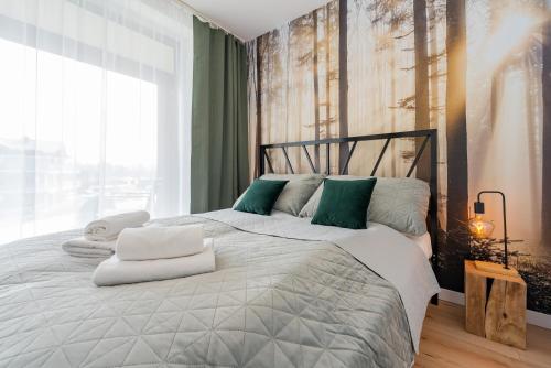 a bedroom with a large bed with green and white pillows at Apartament Mglisty Poranek - Laguna Beskidów - Dream Apart in Zarzecze