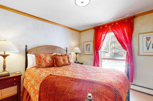 a bedroom with a bed with red curtains and a window at The Village Glen in Vail