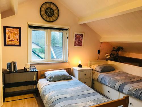 duas camas num quarto com um relógio na parede em Het Uilennest em Exloo