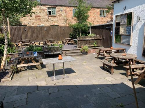 a patio with wooden tables and benches and a fence at George and Dragon in Tarvin