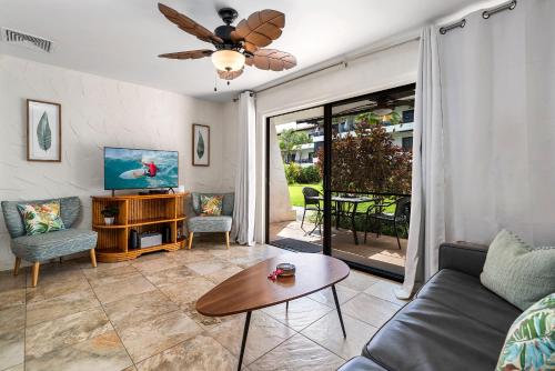 a living room with a couch and a tv and a table at Casa De Emdeko 104 in Kailua-Kona