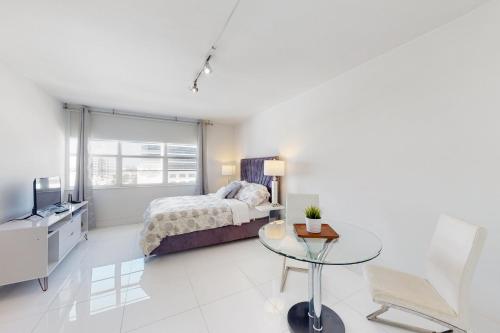 1 dormitorio con cama y mesa de cristal en Decoplage Paradise - Unit A en Miami Beach