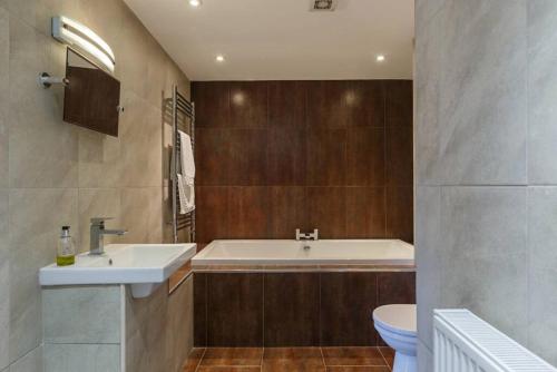 a bathroom with a tub and a sink and a toilet at NEW The Green House Cromer Sleeps 20 Hot Tub in Thorpe Market