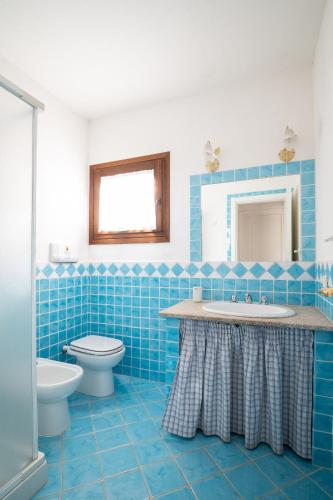 a blue tiled bathroom with a sink and a toilet at Bellosguardo 4 - Klodge in Olbia