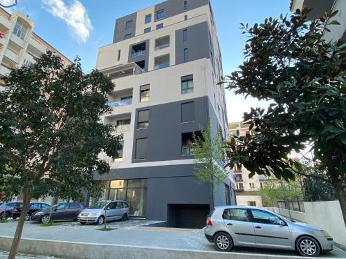 a tall building with cars parked in a parking lot at Apartment Aulona Park in Vlorë