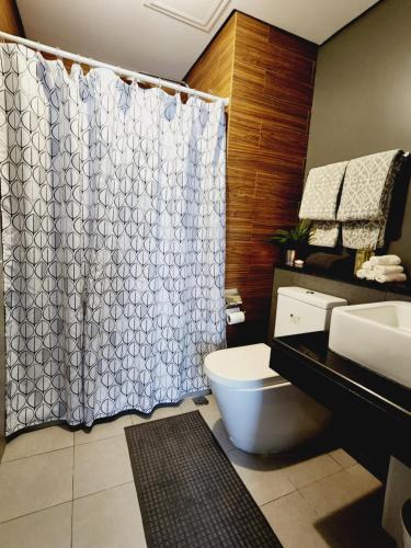 a bathroom with a toilet and a shower curtain at Abode at The Radiance Manila Bay in Manila