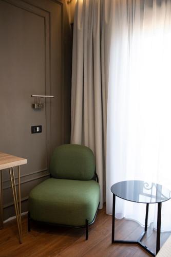 a green chair and a glass table in front of a window at Cosmopolita Boutique Hotel in Timişoara