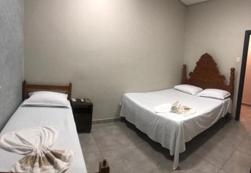 um quarto com duas camas com lençóis brancos em Hotel Cuiabá em Cuiabá