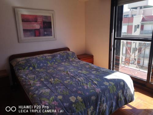 una camera da letto con un letto con un piumone blu e una finestra di 2 amb Maral 48 Mar del Plata a Mar del Plata