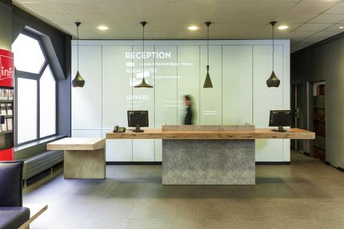 a person sitting at a reception desk in a library at ibis Gent Centrum Opera in Ghent