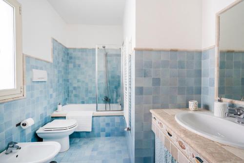 Baño de azulejos azules con aseo y lavamanos en Bella Bari en Bari