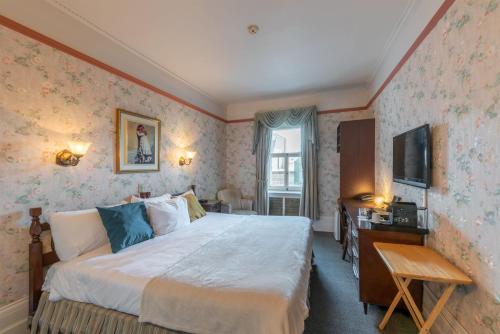 a bedroom with a bed and a desk and a television at Le Chateau de Pierre in Quebec City